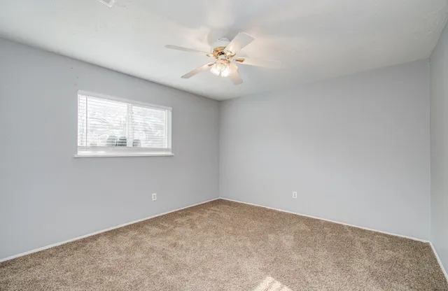 an empty room with a window and a ceiling fan