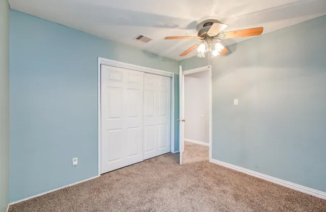an empty room with a chandelier fan and closet