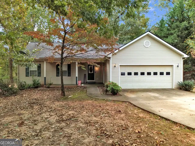 a view of a house with a yard plants and large tree