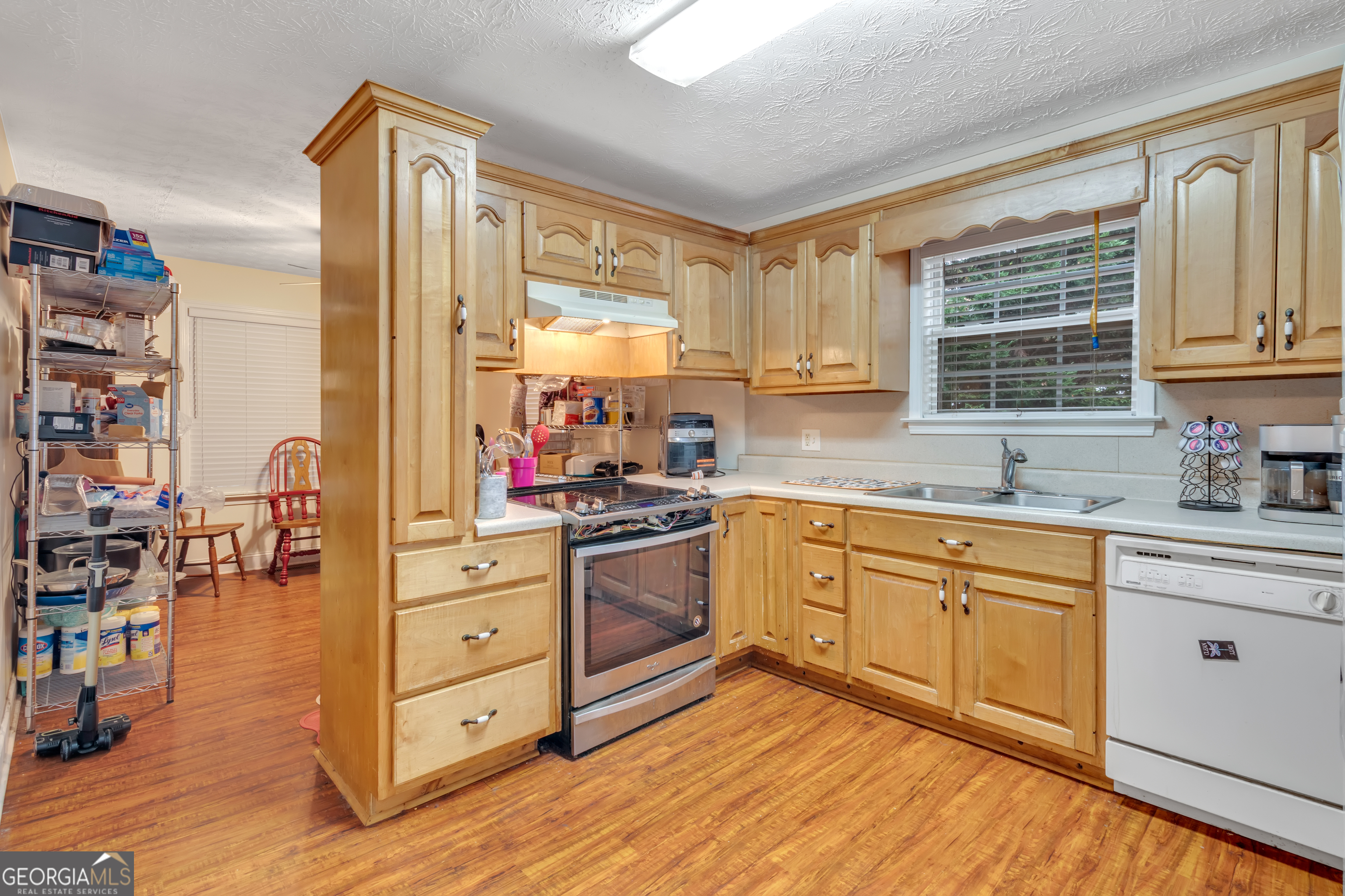 66 Ellis Trail Covington, GA 30016 - Photo 24 of 39 a kitchen with stainless steel appliances sink cabinets and wooden floor
