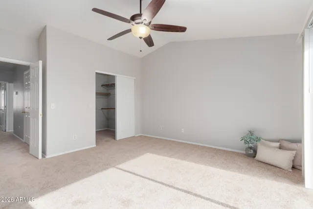an empty room with a chandelier fan and windows