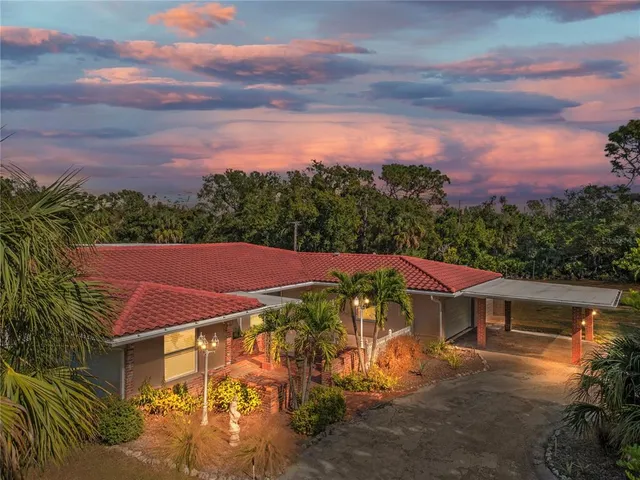 a view of a big house with a yard and table