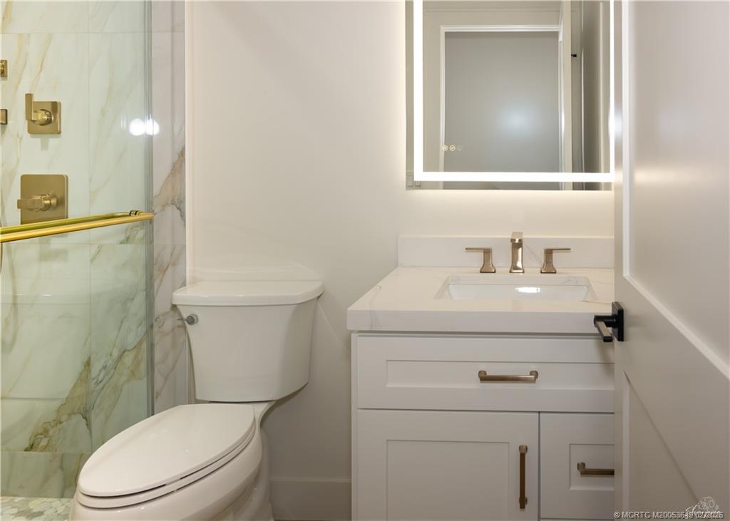 2425 Southwest Foxpoint Trail Palm City, FL 34990 - Photo 23 of 31 a bathroom with a sink a toilet and a mirror