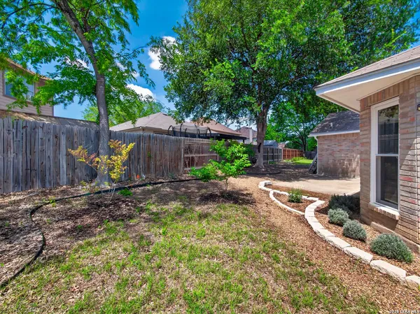 a view of a backyard with large trees and wooden fence