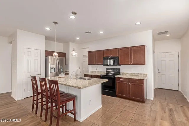 a kitchen with stainless steel appliances granite countertop a stove top oven a sink a dining table and chairs