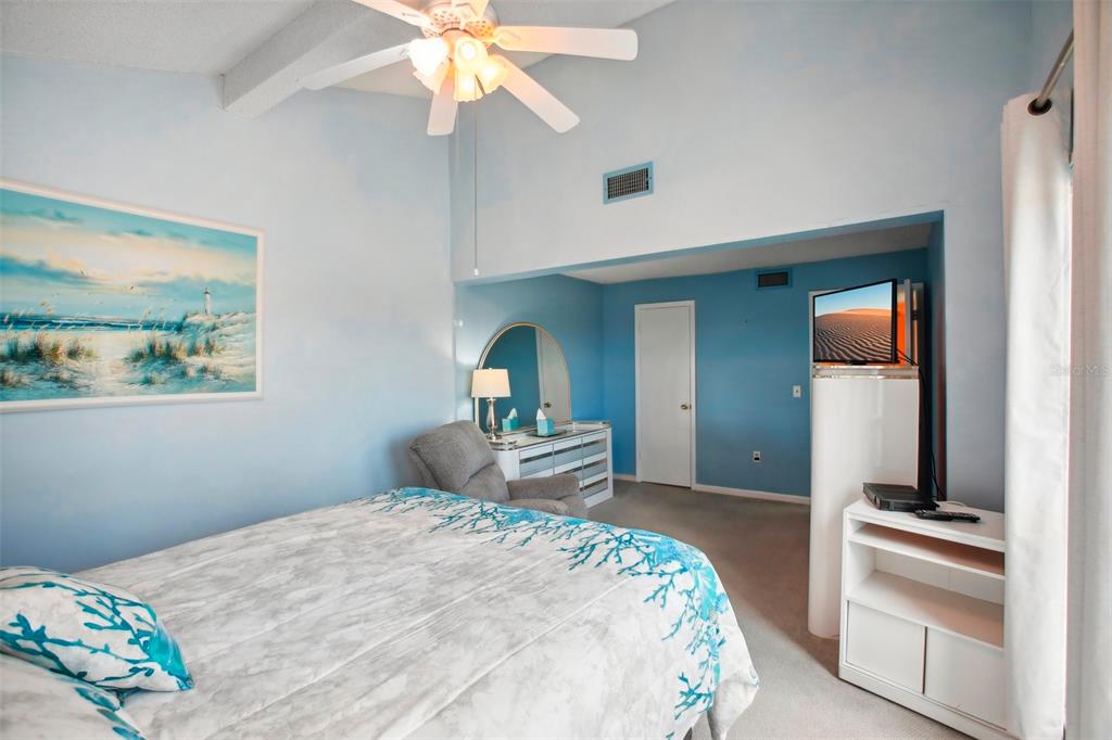 343 Rex Place, Unit F Madeira Beach, FL 33708 - Photo 15 of 28 a bedroom with a bed and a chandelier