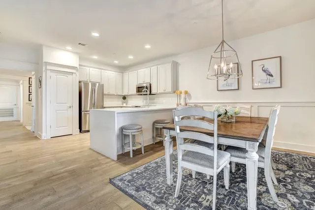 a kitchen with stainless steel appliances kitchen island granite countertop a table chairs sink and cabinets