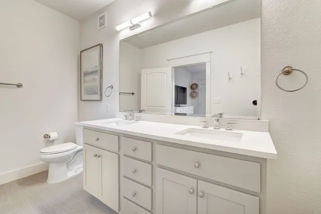 a bathroom with a toilet sink double vanity and mirror
