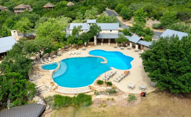 an aerial view of a house with swimming pool and large trees