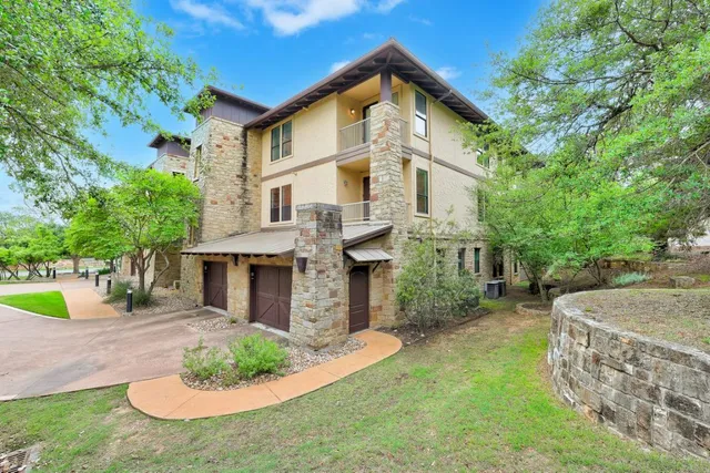 a view of a white house next to a yard with plants and trees