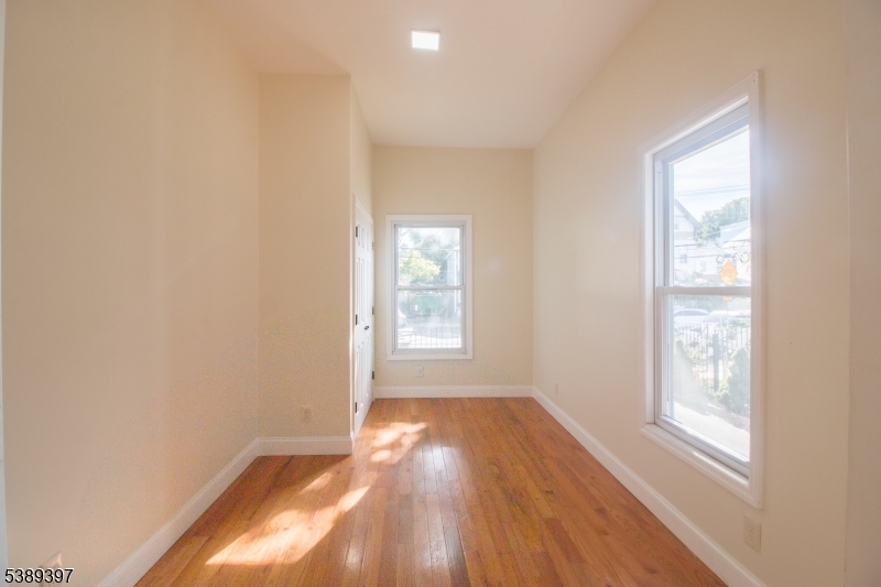 187 Littleton Avenue, Unit 1 Newark, NJ 07103 - Photo 16 of 22 an empty room with wooden floor and windows