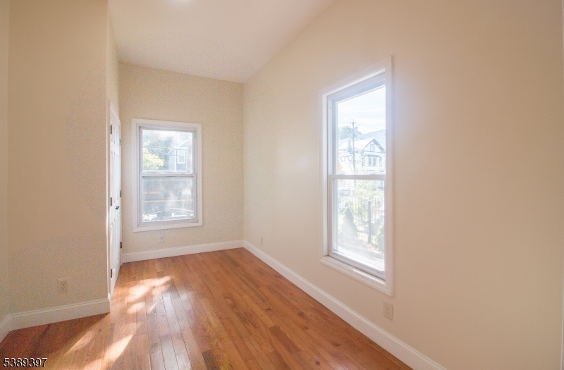 187 Littleton Avenue, Unit 1 Newark, NJ 07103 - Photo 21 of 22 a view of an empty room with wooden floor and a window