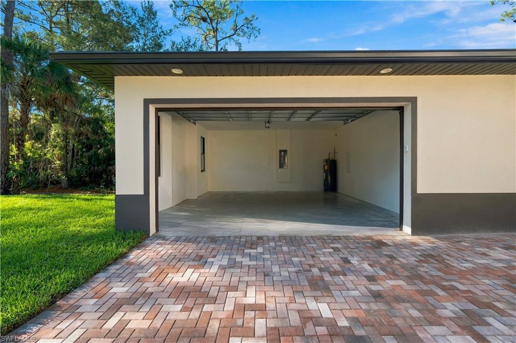 183 5th Street Southwest Naples, FL 34117 - Photo 32 of 40 Multi-tone paver driveway, an attached garage with an open bay, and a concrete floor