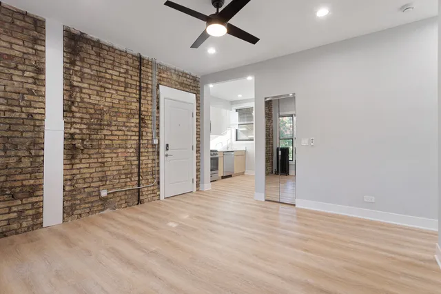 a view of an empty room with wooden floor and a ceiling fan