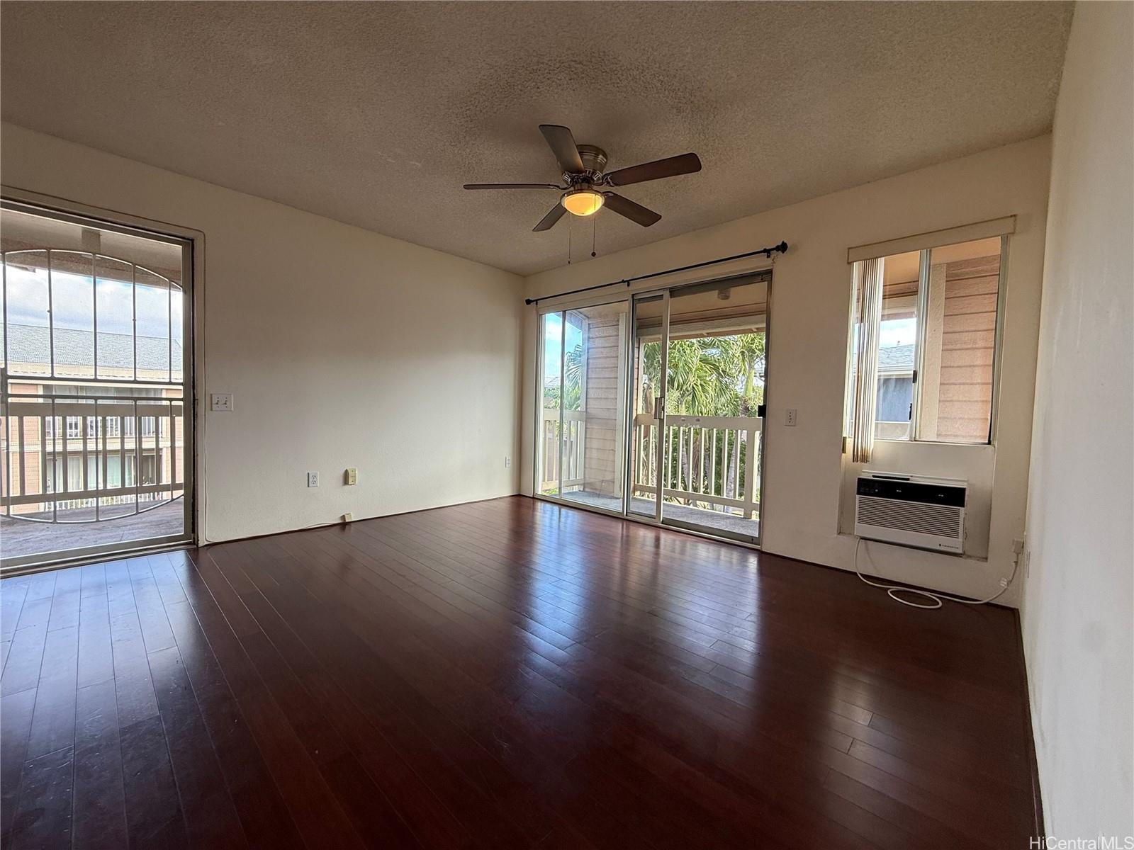 a view of empty room with wooden floor and fan