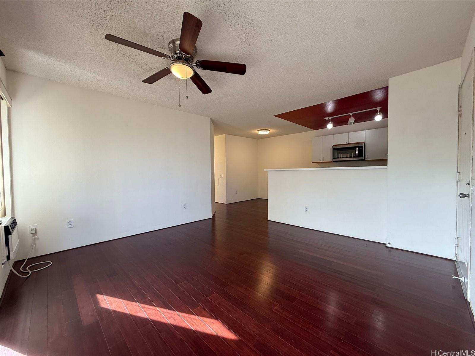 91-1199 Kaneana Street, Unit 2D Ewa Beach, HI 96706 - Photo 2 of 12 a view of an empty room with wooden floor and a ceiling fan