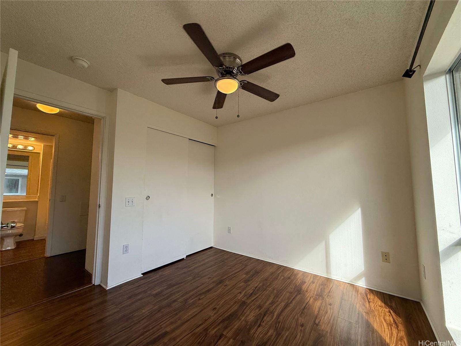 91-1199 Kaneana Street, Unit 2D Ewa Beach, HI 96706 - Photo 7 of 12 a view of an empty room with wooden floor and a window