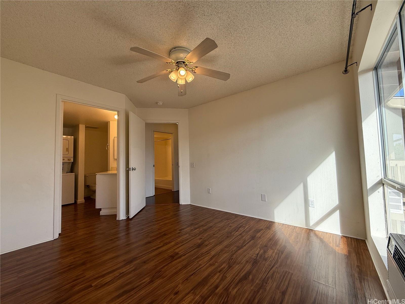 91-1199 Kaneana Street, Unit 2D Ewa Beach, HI 96706 - Photo 10 of 12 a view of an empty room with wooden floor and a window