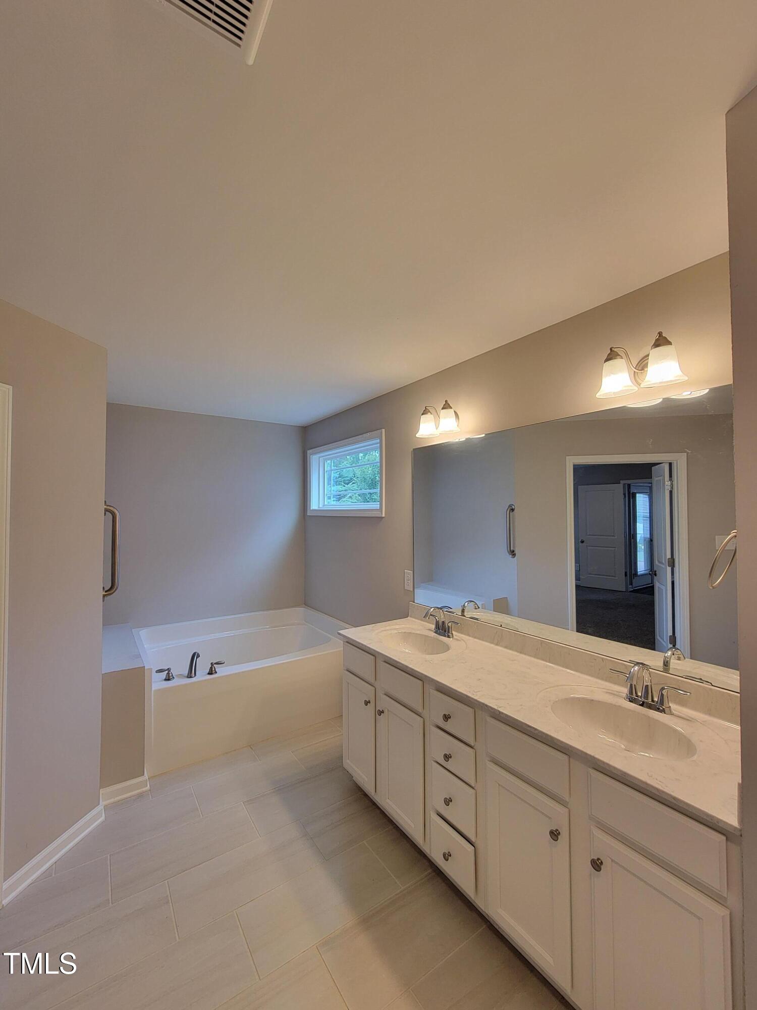 72 Mountain View Drive Garner, NC 27529 - Photo 19 of 22 a spacious bathroom with a double vanity sink a mirror and a bathtub