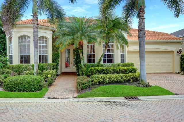 front view of a house with a yard and palm trees