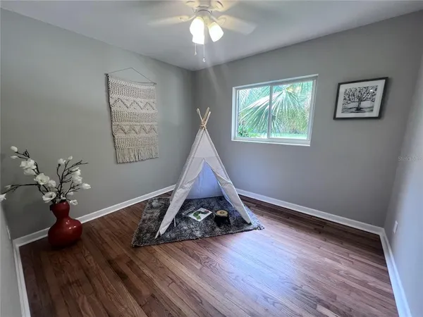 a view of an empty room with wooden floor and a window