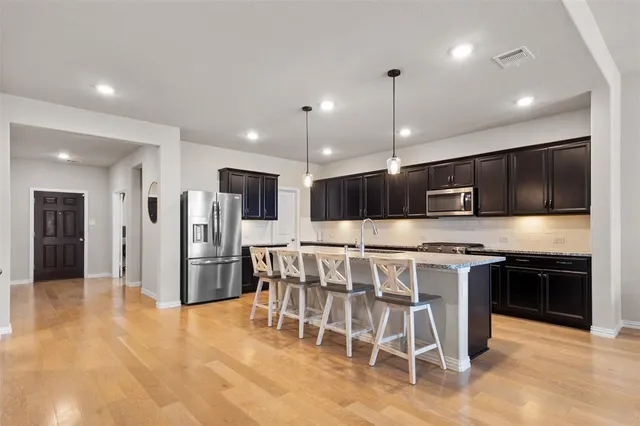a kitchen with stainless steel appliances kitchen island granite countertop a table and chairs in it