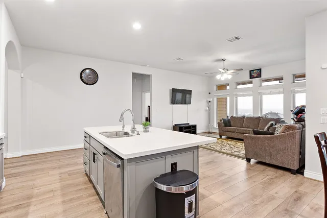 a living room with stainless steel appliances furniture a rug and a kitchen view