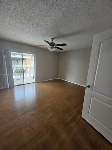 an empty room with wooden floor fan and windows
