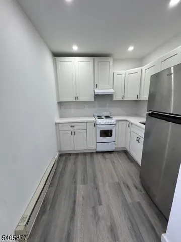 a kitchen with sink a refrigerator and white cabinets