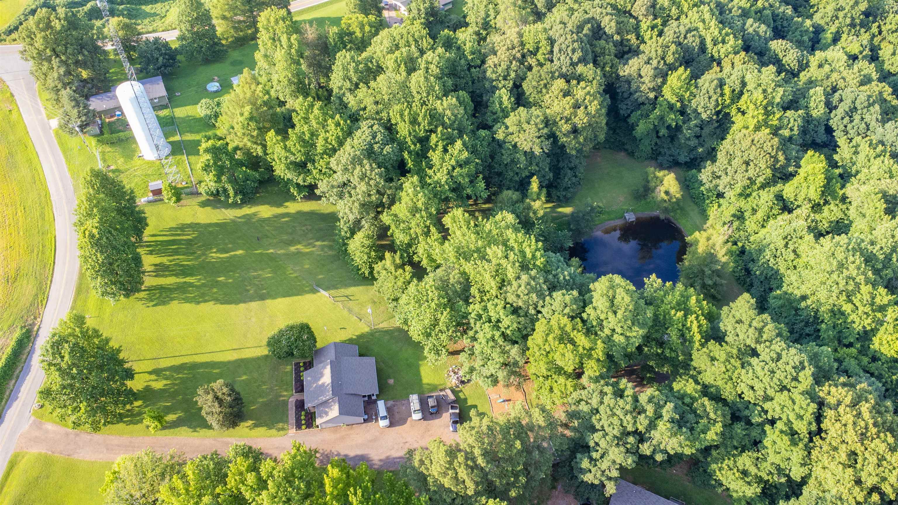 120 Craig Road Ripley, TN 38063 - Photo 2 of 38 Expansive property featuring a private pond, mature tree coverage, and a residential structure with a dark shingle roof