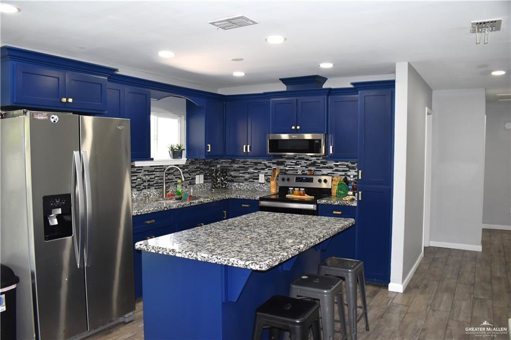 1005 Adams Street Mission, TX 78572 - Photo 3 of 3 a kitchen with refrigerator and a wooden cabinets
