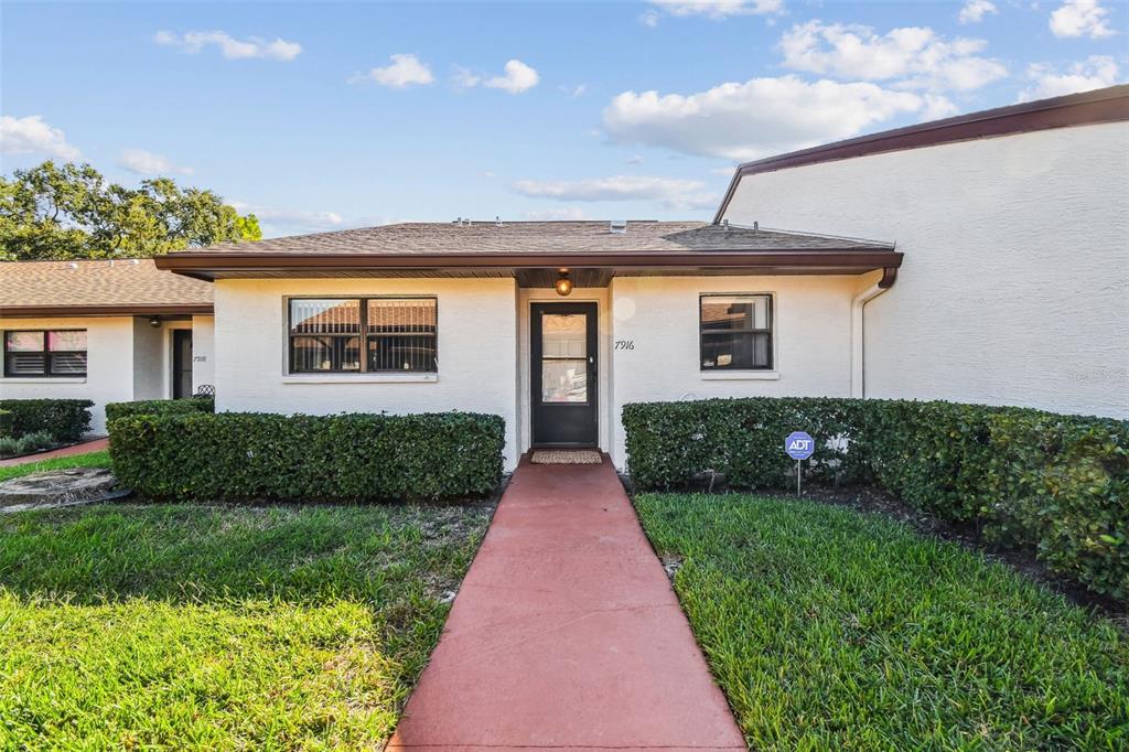 a front view of a house with a yard and potted plants