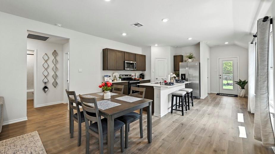 646 Glee Stem Road Lavon, TX 75166 - Photo 13 of 17 Open-concept living space featuring wood-finish flooring, recessed lighting, and a kitchen island with seating