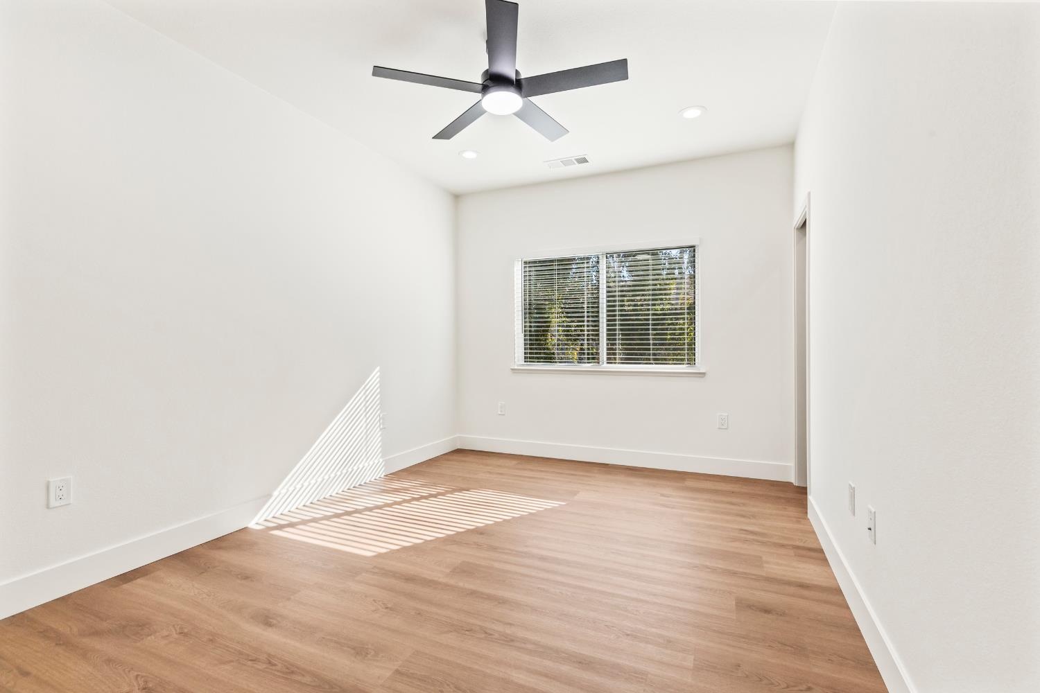 688 Cindy Drive Ripon, CA 95366 - Photo 38 of 57 an empty room with wooden floor chandelier fan and windows