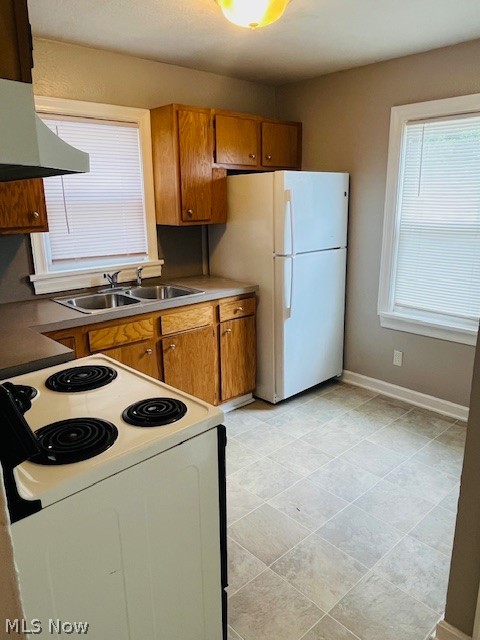 2918 9th Street Northwest Canton, OH 44708 - Photo 11 of 16 Kitchen featuring wall chimney range hood, sink, light tile flooring, and white appliances
