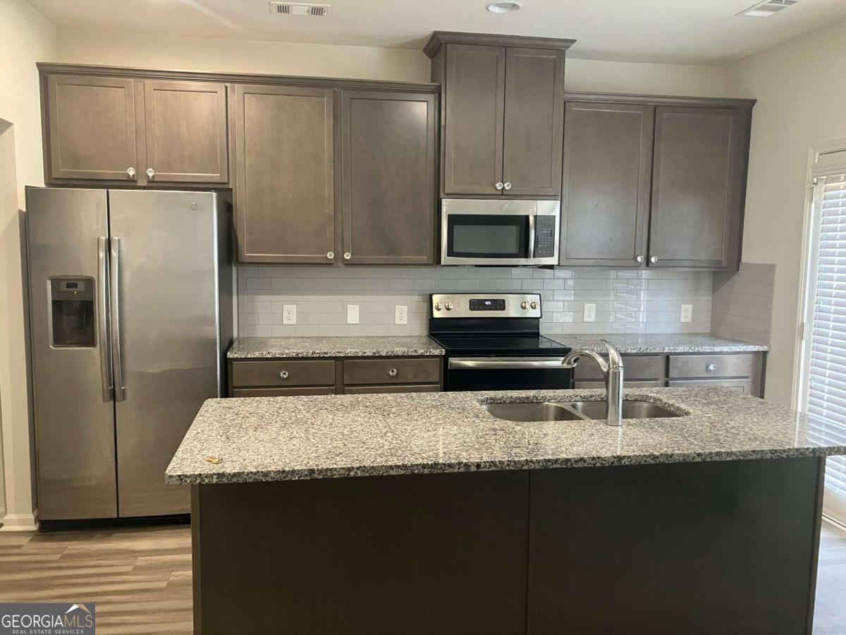 5243 Mill Way Stone Mountain, GA 30083 - Photo 3 of 15 a kitchen with granite countertop a refrigerator a sink and wooden cabinets