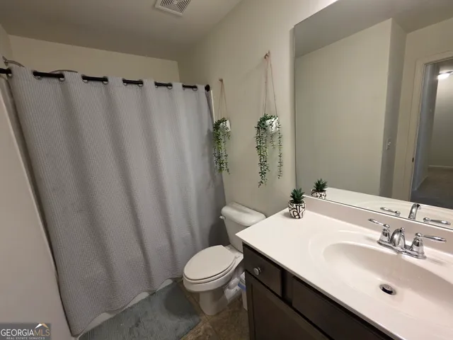 a bathroom with a sink a toilet a mirror and shower curtain