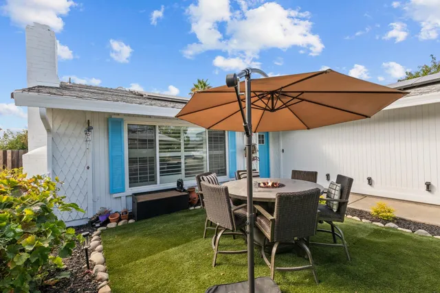 a patio with a table and chairs under an umbrella