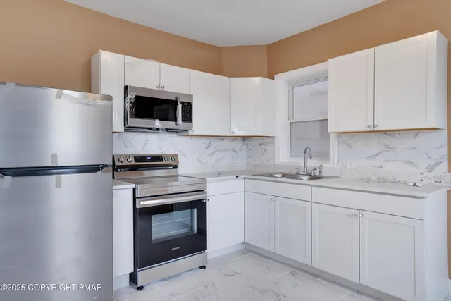 a kitchen with stainless steel appliances white cabinets white stove a microwave and a sink