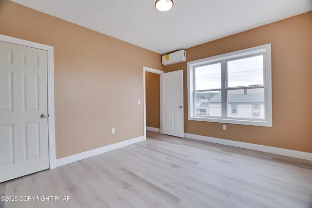 a view of an empty room with window and wooden floor