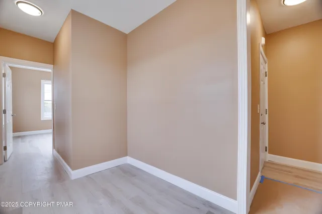 a view of an empty room with wooden floor and a bathroom