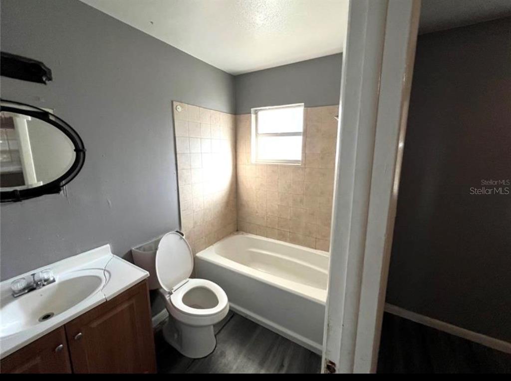 7004 Clarcona Ocoee Road Orlando, FL 32818 - Photo 7 of 10 a white toilet sitting next to a bathroom sink and tub