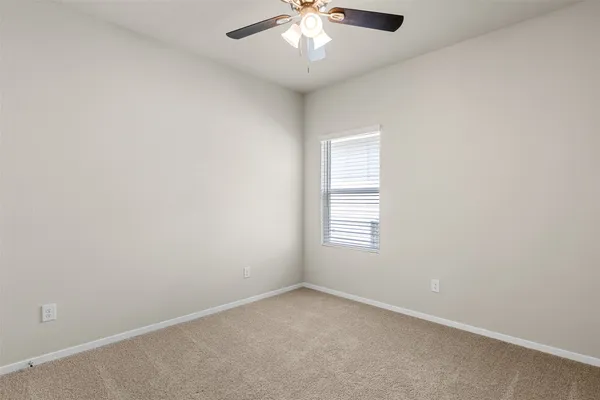 an empty room with windows and ceiling fan