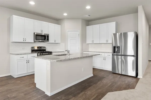 a kitchen with stainless steel appliances granite countertop a stove a sink and a microwave