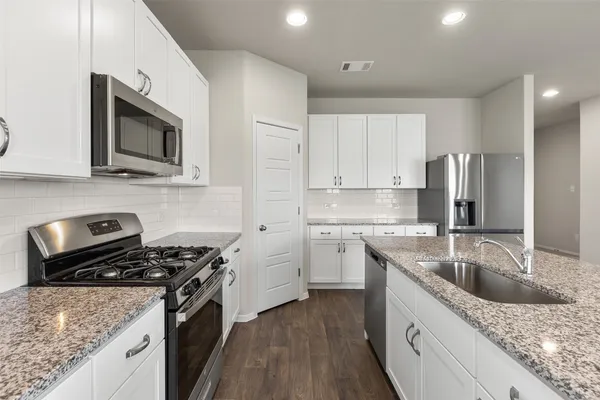 a kitchen with white cabinets and stainless steel appliances