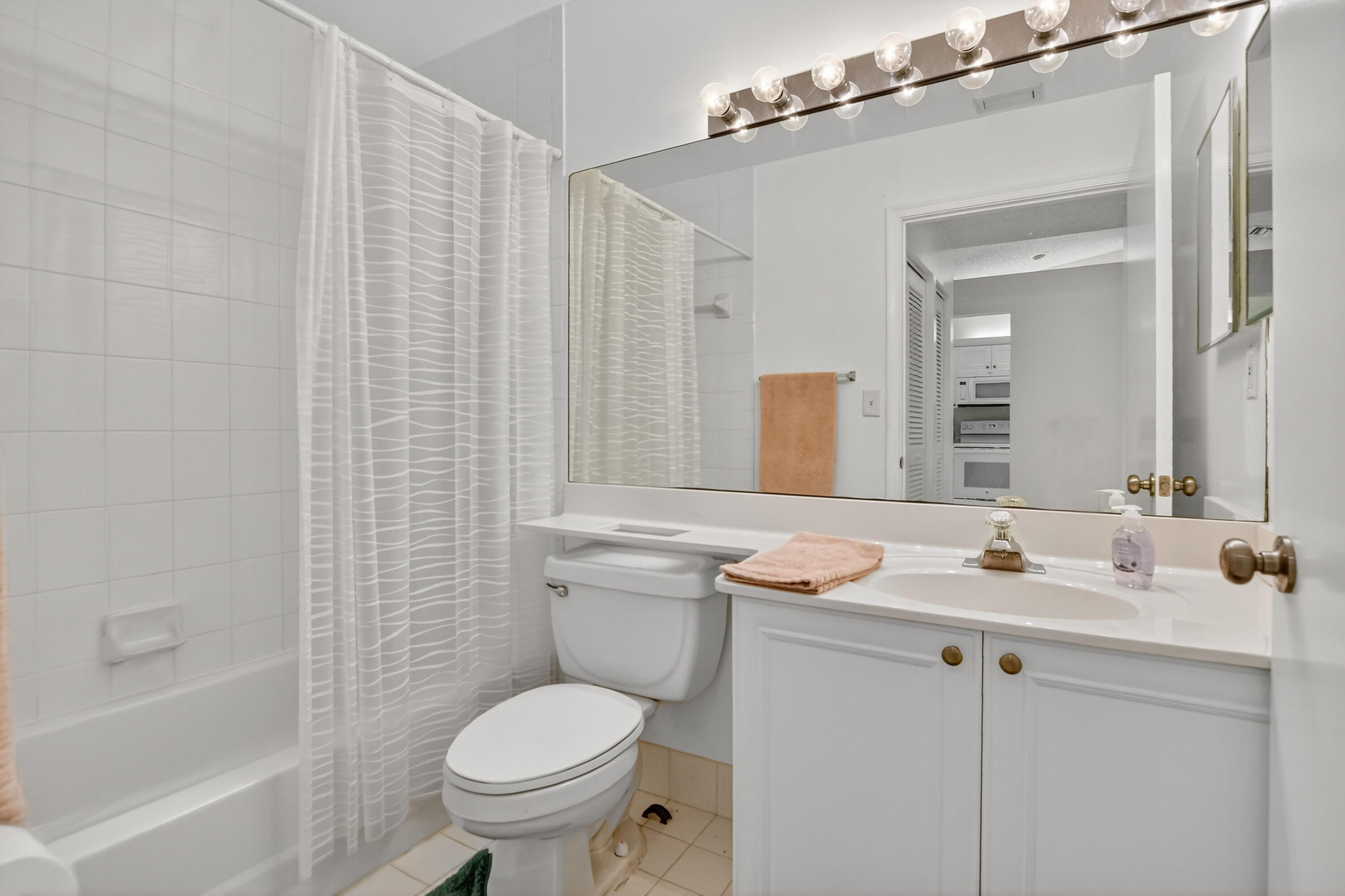 380 Northwest 67th Street, Unit 207 Boca Raton, FL 33487 - Photo 11 of 34 a bathroom with a granite countertop toilet sink and mirror