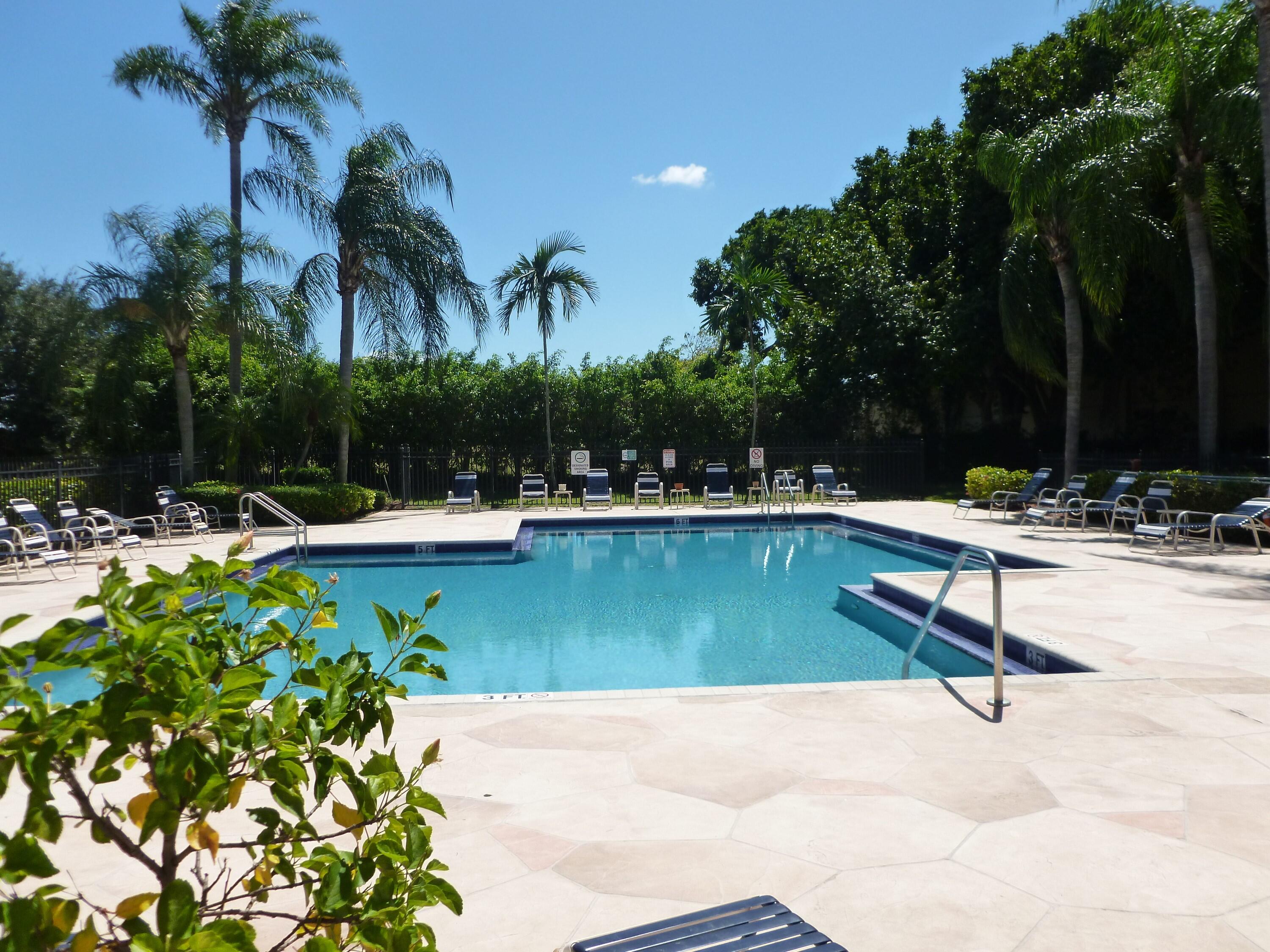 380 Northwest 67th Street, Unit 207 Boca Raton, FL 33487 - Photo 22 of 34 a swimming pool with outdoor seating and trees