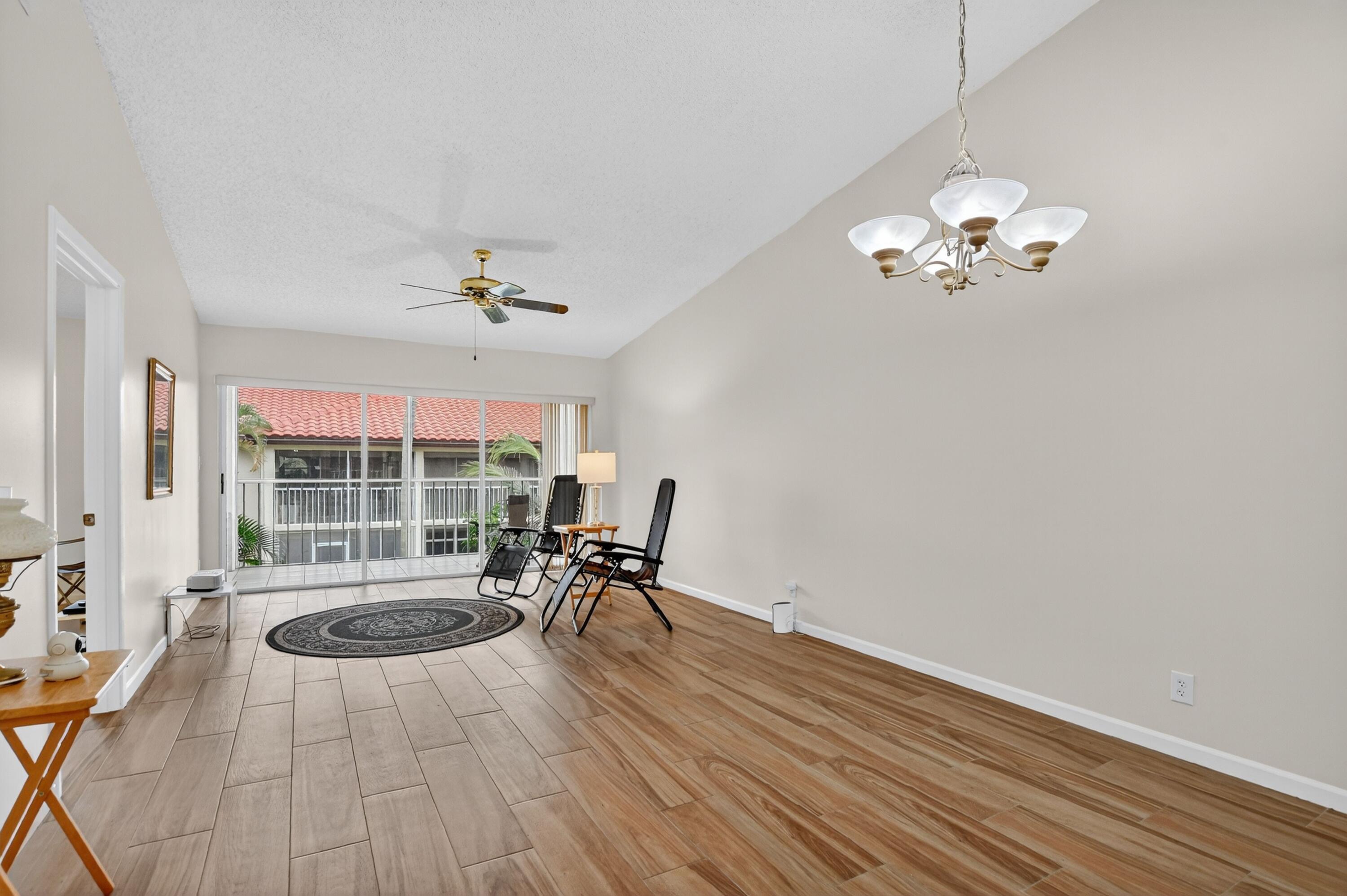 380 Northwest 67th Street, Unit 207 Boca Raton, FL 33487 - Photo 6 of 34 a view of a livingroom with wooden floor and a chandelier