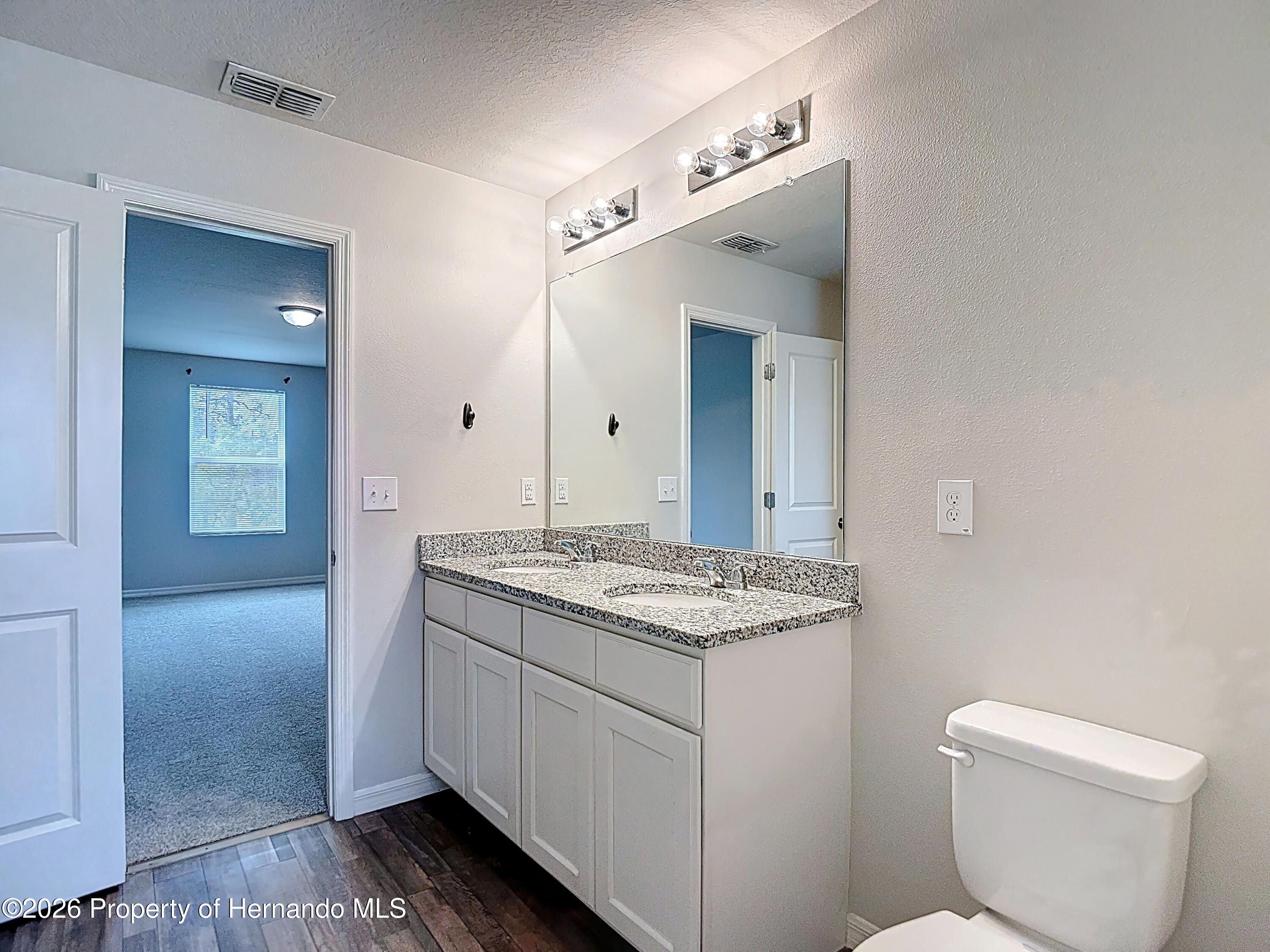 11374 Marcella Avenue Weeki Wachee, FL 34614 - Photo 43 of 70 a bathroom with a granite countertop sink a toilet and mirror