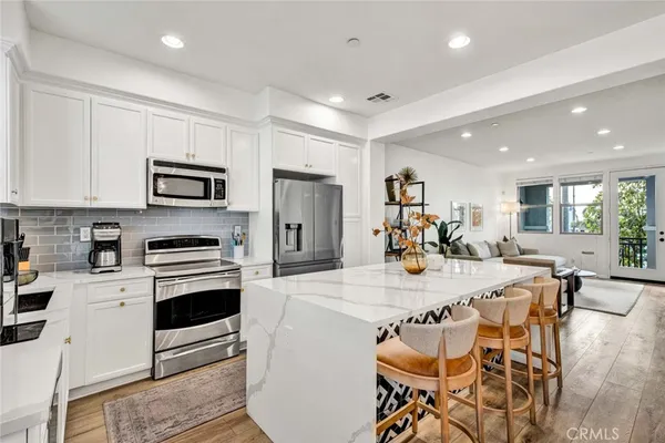 a kitchen with stainless steel appliances kitchen island granite countertop a stove a sink a dining table and chairs